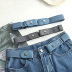 Light blue no-buckle belt fastened around the front belt loops of jeans, with blue and gray belts above