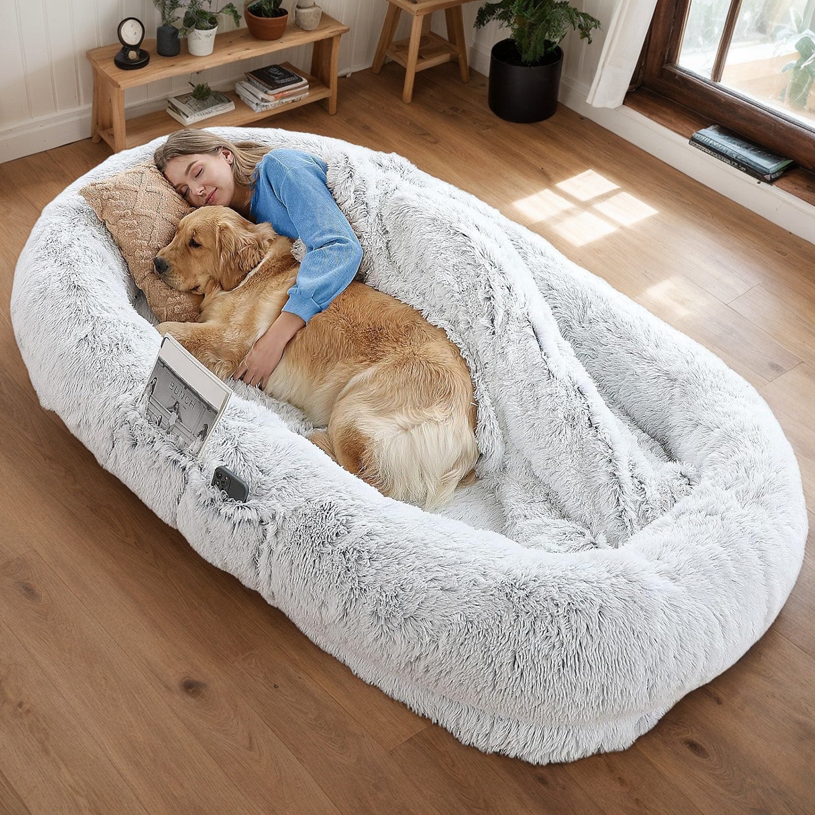 Woman relaxing on human-size dog bed with golden retriever, overhead view